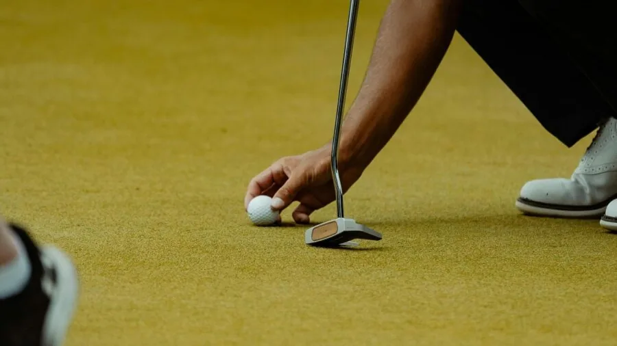 Golfer holding umbrella on wet golf course during rainy weather conditions