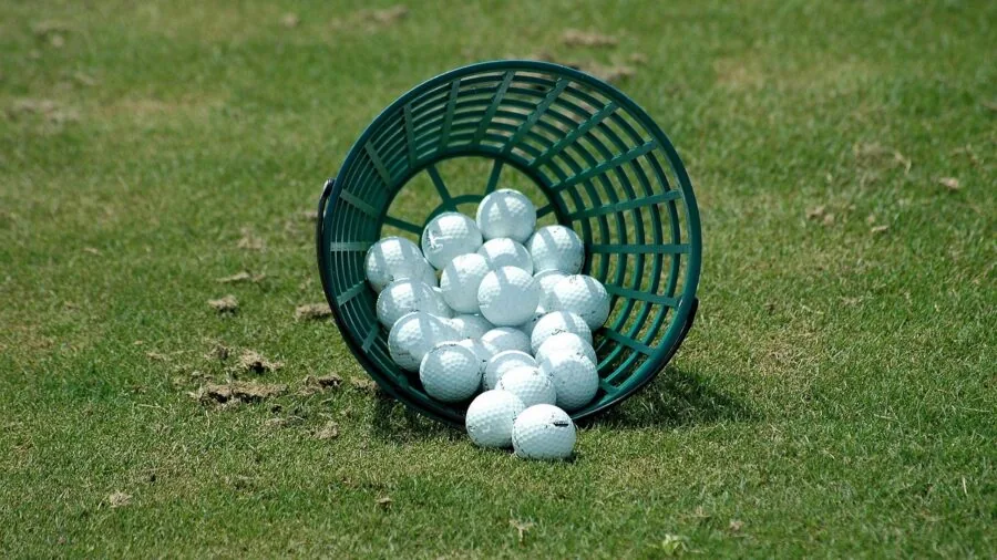 Golfer in casual attire practicing golf swing on sunny course with natural landscape