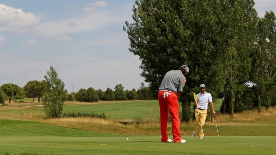 Golfer in collared polo shirt standing on golf course preparing for shot