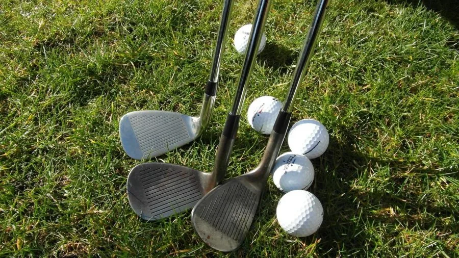 Golfer in mid-swing hitting a wedge shot from the fairway during a round of golf