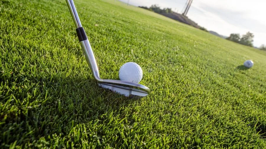 Golfer in modern athletic wear walking across a lush golf course fairway during golden hour