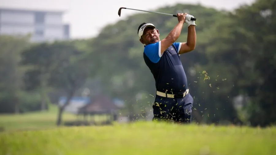 Golfer mid-swing hitting golf ball with natural motion blur on fairway