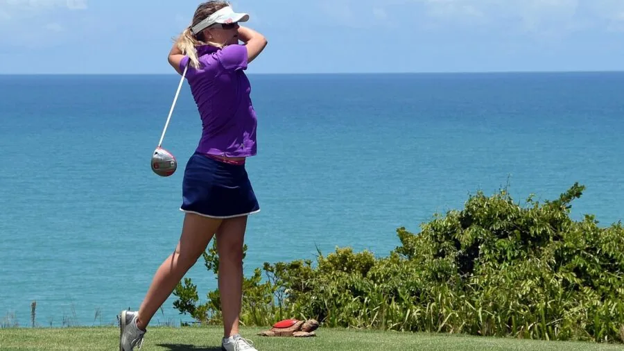 Golfer mid-swing on a sunny golf course demonstrating proper iron technique and form