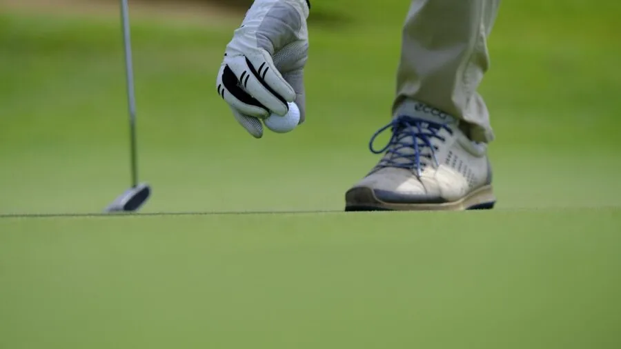 Golfer mid-swing on driving range with ball in flight against natural background