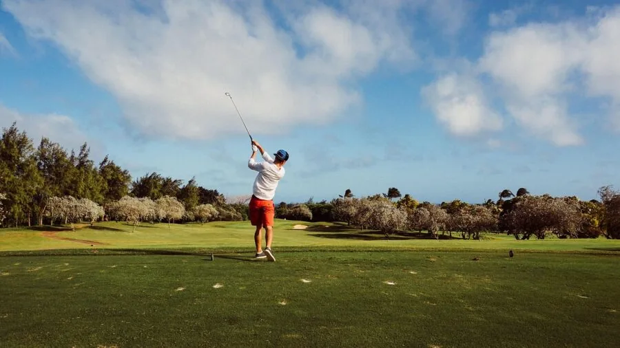 Golfer mid-swing on grass course demonstrating golf technique and form during play