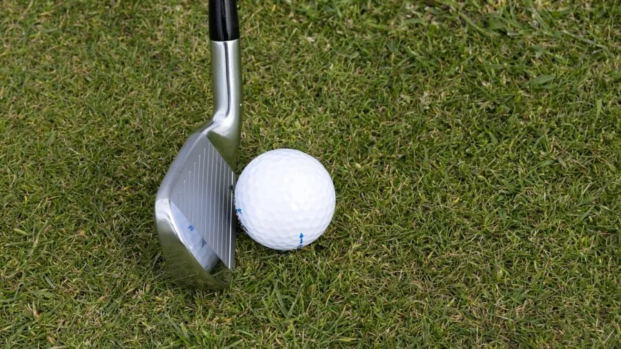 Golfer mid-swing with iron club on golf course grass