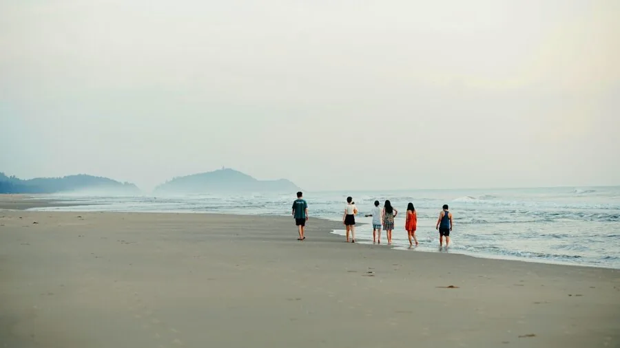 Group of friends playing roundnet game on sunny beach with focused expressions