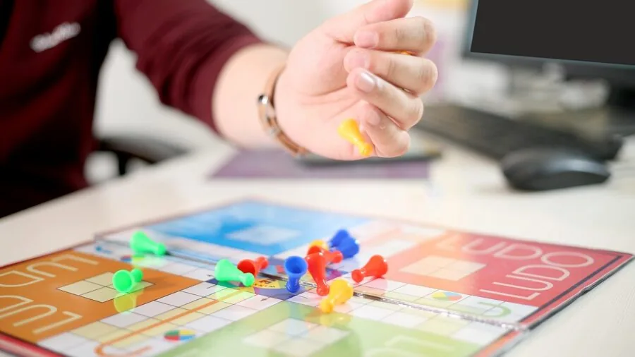 Group of people gathered around a table playing a strategy board game, deliberating moves