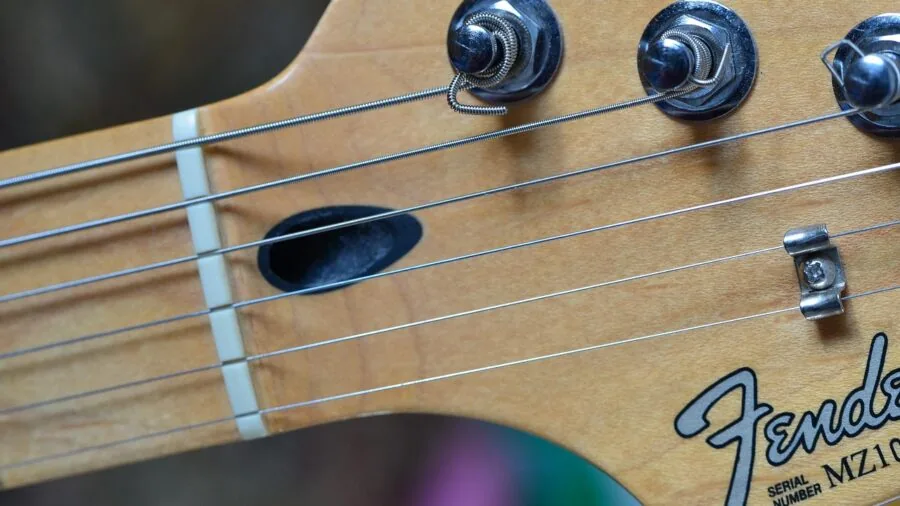 Guitarist adjusting tuner on electric guitar headstock during practice session
