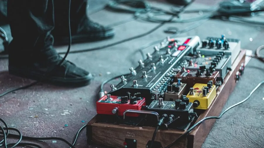 Guitarist arranging cable connections on pedalboard setup during rehearsal session