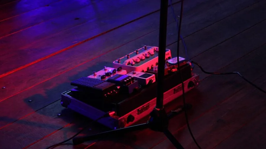 Guitarist organizing and connecting guitar pedals in signal chain setup for tone shaping