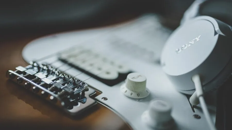 Guitarist's hands adjusting pickup settings on electric guitar during practice session