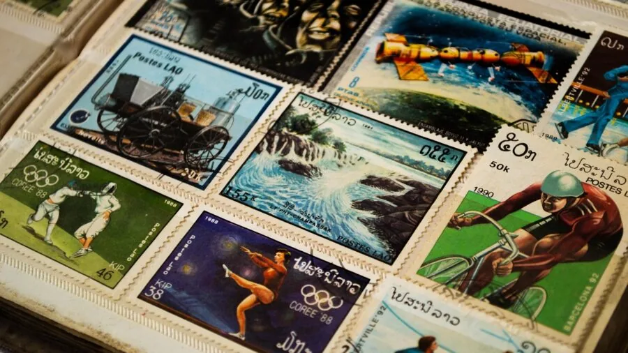 Hands carefully organizing old stamps in archival album pages with natural lighting