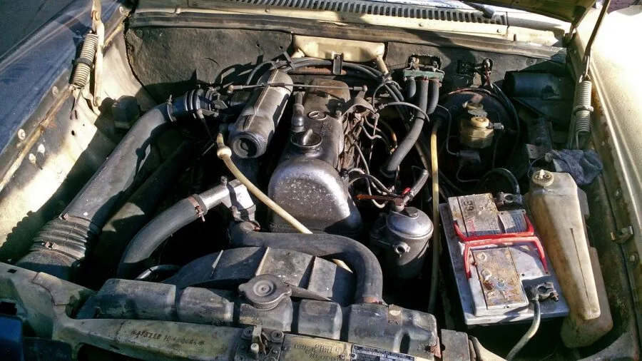 Hands cleaning battery terminals with spray cleaner on car engine