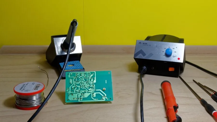 Hands performing detailed electronic soldering work with fine wire and concentrated focus on circuit board assembly