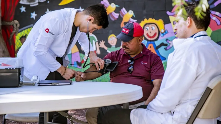 Healthcare professional measuring patient's blood pressure with medical device during clinical examination