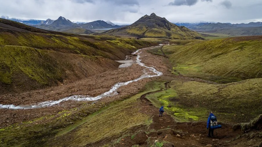 Hiker filling water bottle from mountain stream during outdoor adventure