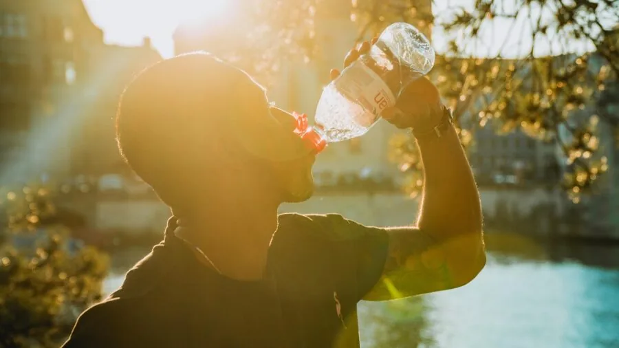 Hiker gripping water bottle during outdoor trail walk, demonstrating ergonomic handle usage