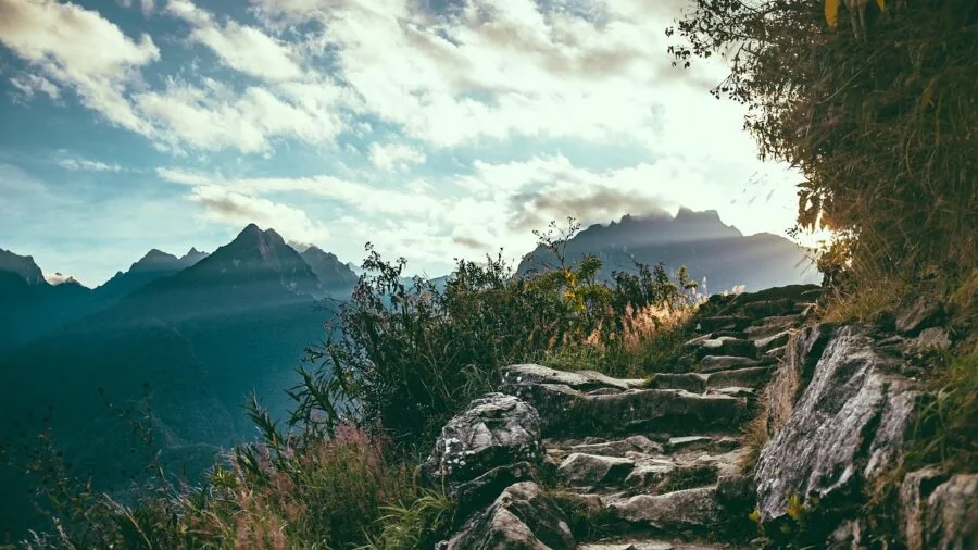Hiker in boots navigating rocky terrain on mountain trail