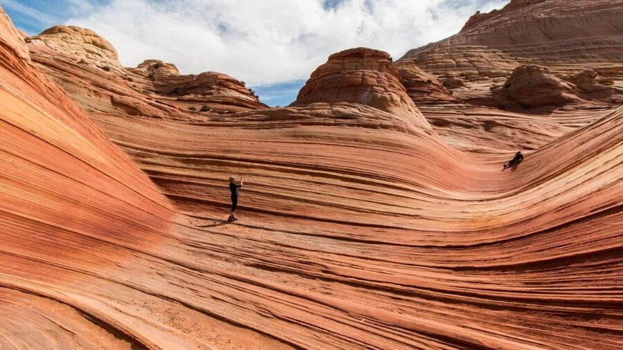 Hiker in desert landscape drinking from water bottle during backcountry trek