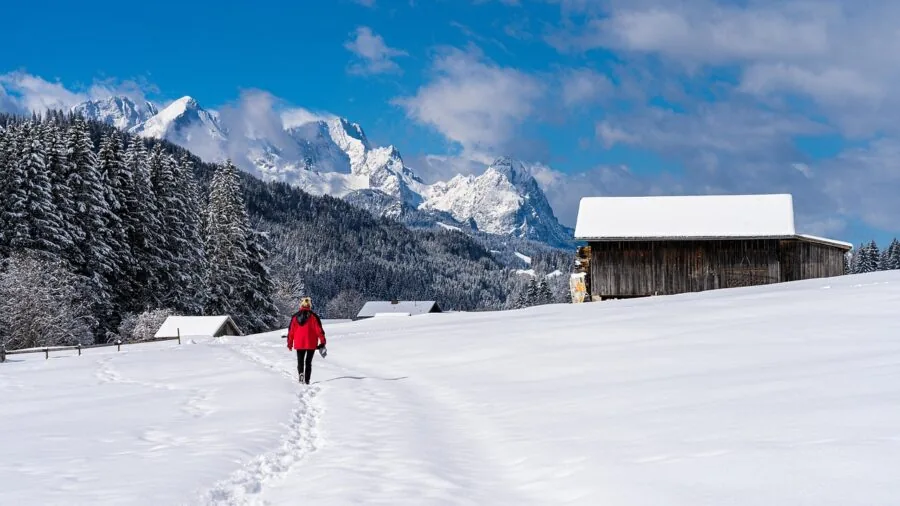 Hiker in winter gear walking through snowy mountain terrain during cold weather adventure