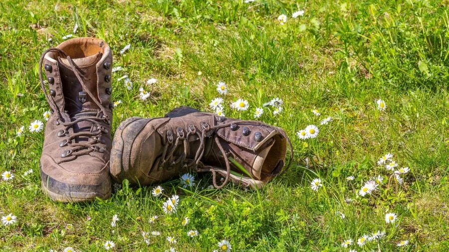 Hiker inspecting hiking boot leather material on mountain trail
