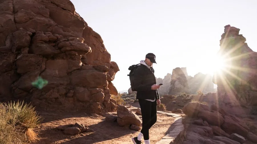 Hiker trekking through mountain landscape with backpack and camera equipment
