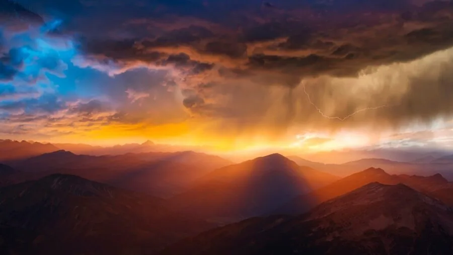 Hiker trekking through rainy mountain terrain with heavy rainfall and clouds