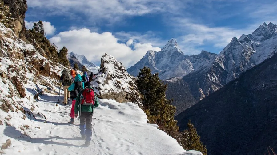 Hiker trekking through snowy mountain landscape in cold weather conditions