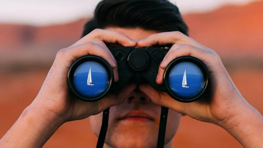 Hiker using binoculars to observe distant mountain landscape during outdoor adventure