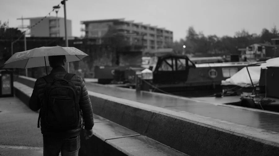 Hiker with backpack traversing wet terrain in challenging weather conditions during outdoor adventure