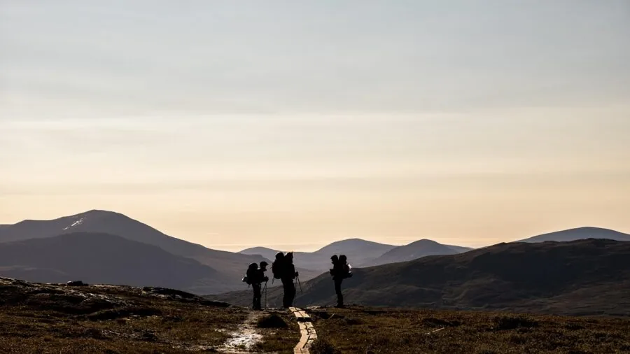 Hiker with backpack walking on mountain trail through wilderness landscape