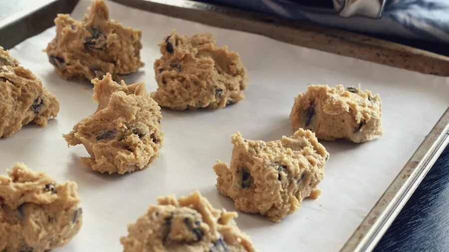 Home baker arranging cookie dough on large baking sheet in bright kitchen