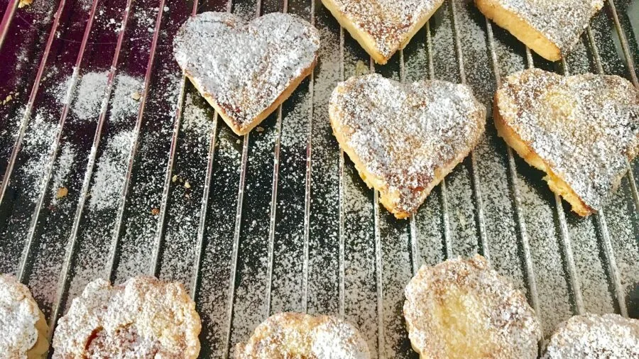 Home baker arranging unbaked cookies on a rimmed baking sheet in bright kitchen