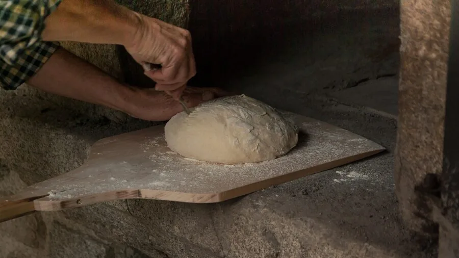 Home baker monitoring oven heat while baking bread in kitchen