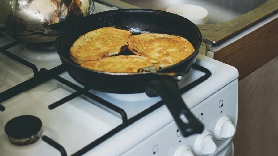 Home cook carefully handling a heavy roasting pan with oven mitts in a warm kitchen setting
