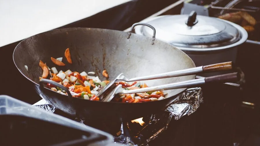 Home cook holding pan handle while cooking at stove in kitchen