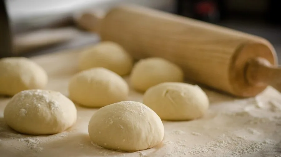 Home cook measuring flour in bowl during baking preparation in bright kitchen