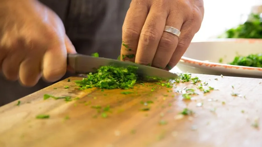 Home cook preparing fresh ingredients on wooden cutting board in natural kitchen lighting