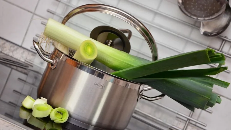 Home cook safely handling a large pot of boiling water on stovetop with proper grip