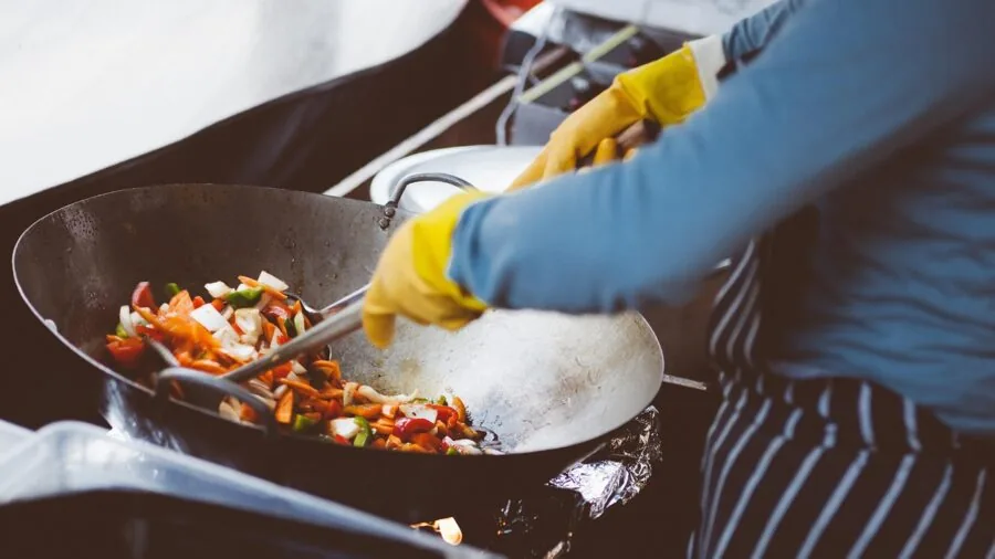 Home cook stirring food in wok with long handle during meal preparation in bright kitchen