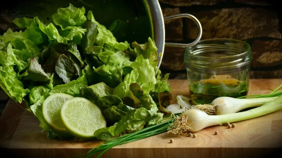 Home cook tossing fresh greens in kitchen while preparing healthy salad meal