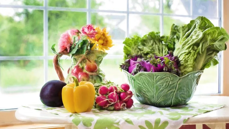 Home cook washing and preparing fresh vegetables in a bright kitchen sink for salad preparation