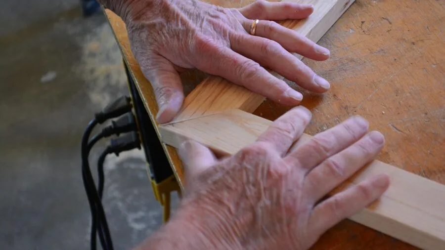 Home woodworker carefully cutting curved wood on a compact benchtop tool in a bright workshop