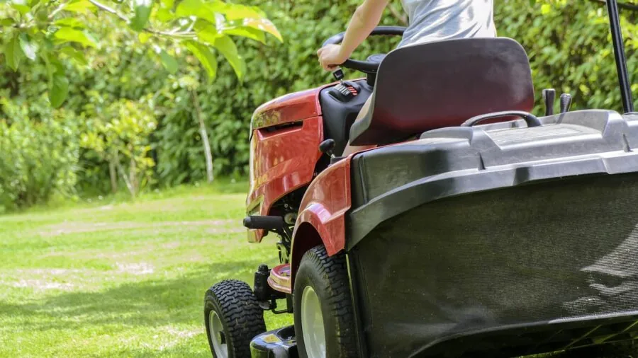 Homeowner operating a lawn mower across a green residential yard during yard maintenance
