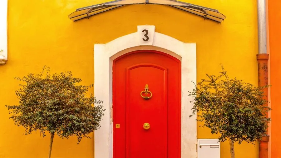 Illuminated home exterior at dusk with bright security lighting highlighting entryway and landscaping