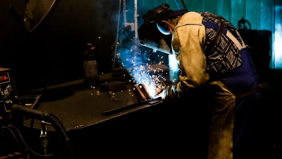 Industrial metalworking workshop with cutting machinery and worker in action