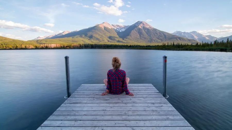 Kayaker paddling on peaceful, flat water lake surrounded by natural scenery