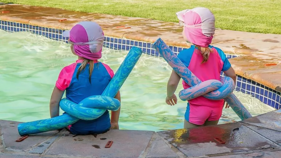 Kids enjoying a colorful inflatable pool in a backyard on a sunny summer day