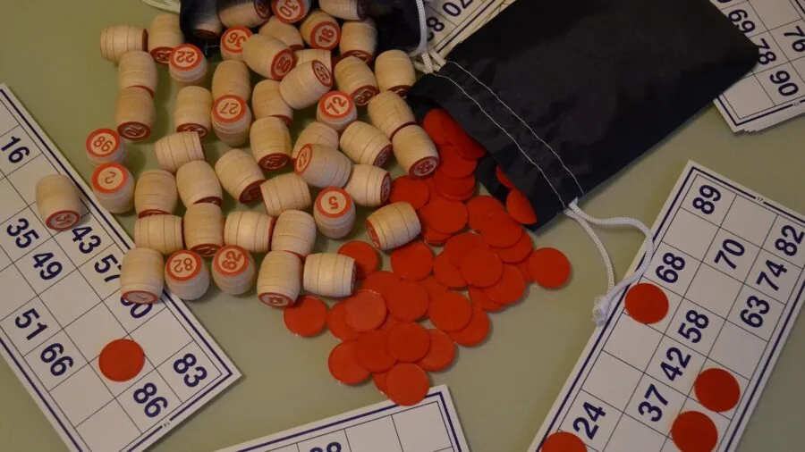 Kids sitting around table playing board game together, showing worn game pieces and cards from repeated use
